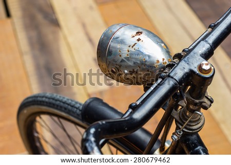 Retro style image of a nineteenth century bicycle on wooden floor , focus to old head lamp  & shallow dept of field