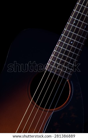 low key vertical image showing part of sunburst acoustic guitar & beautiful rim light of six strings, frets and body shape , isolated on black + copy space for music concept background