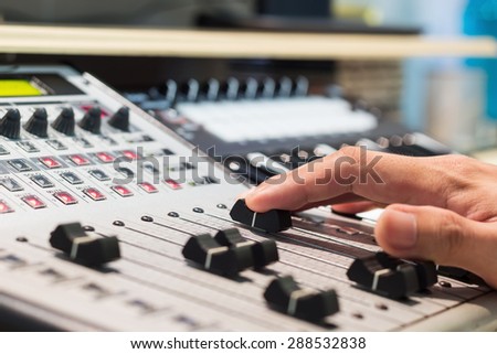 sound engineer right hand on digital studio mixer fader for music recording, radio / tv broadcasting  background