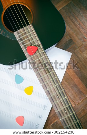 acoustic guitar and colorful picks on music sheet for music background