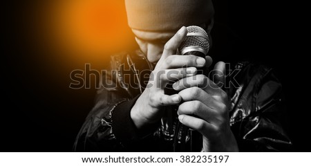 asian handsome singer posing on dynamic microphone. focus on hand, isolated on black