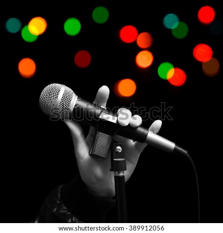 BW singer left hand holding dynamic microphone with colourful bokeh. ( hand sign mean love ) concept = love to sing