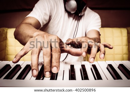 musician hands playing white piano on yellow seat + art filter for music background