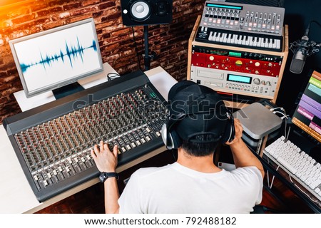 back of asian male music producer, sound engineer, composer, dj working in studio. recording, broadcasting, audio video editing concept
