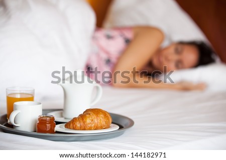 Woman is sleeping in a hotel with breakfast in front of her