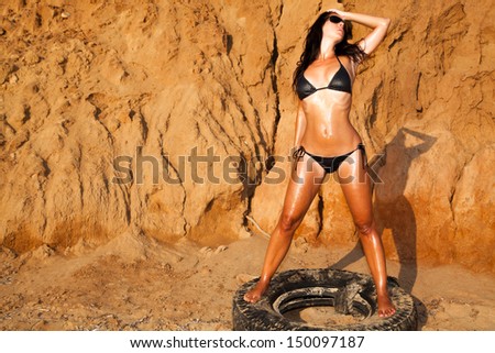 Beautiful woman on a post on the car tire on beach
