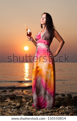Beautiful woman in evening dress on sunset at sea