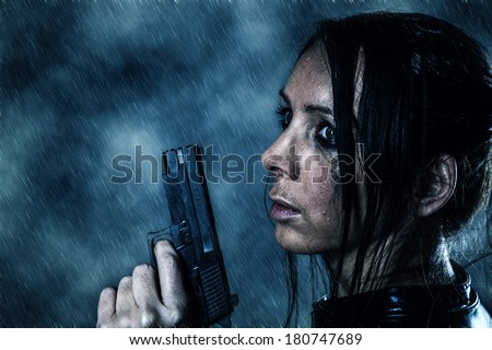 Beautiful girl with a gun in the rain