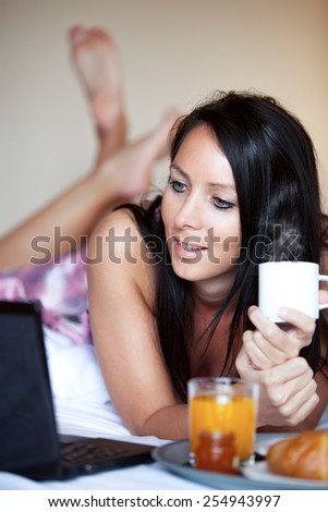 Beautiful woman with notebook and breakfast in a hotel bed