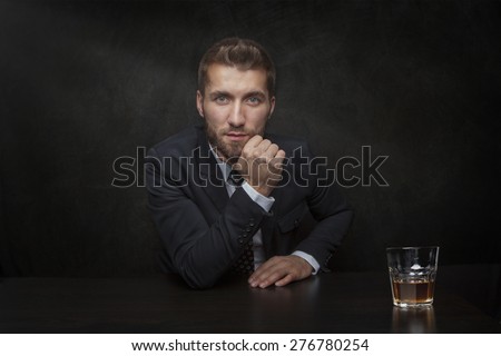 Attractive business man with a glass of whiskey on a black background