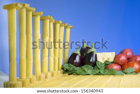 The Roman ruins of pasta with spinach, tomatoes, eggplant and cheese on a blue background.