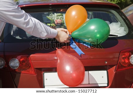 man\'s hand decorating red car before wedding