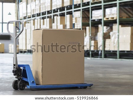 Manual forklift pallet with a big box in a large modern warehouse