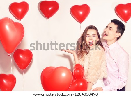 Man with his lovely sweetheart girl dance and have fun at Lover\'s valentine day. Valentine Couple Party. Background red balloons hearts. Love concept. Crazy. Empty copy space for your text.