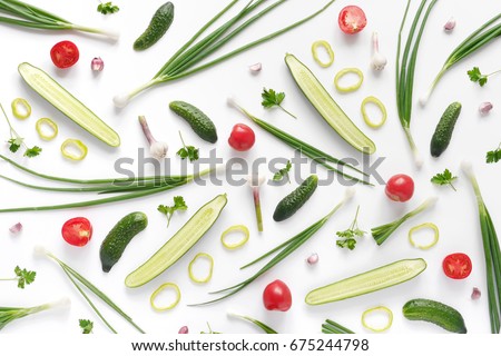Abstract composition of vegetables. Vegetable pattern. Food background. Top view. Large and small cucumbers, garlic, tomatoes and green onions on a white background. Food concept. Sliced vegetables.