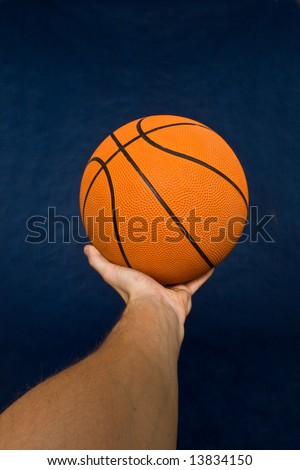 Basketball in men’s hand against a black background