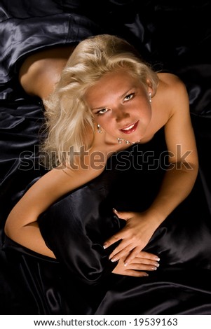 Beautiful young blond girl on black silk.