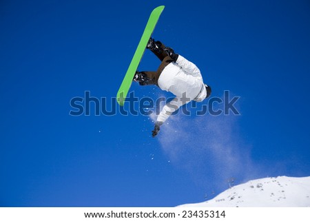 snowboarder taking big air jump with bright blue sky