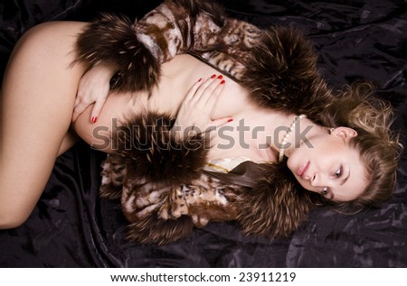 Fashion pregnant woman lying in bed in fur coat