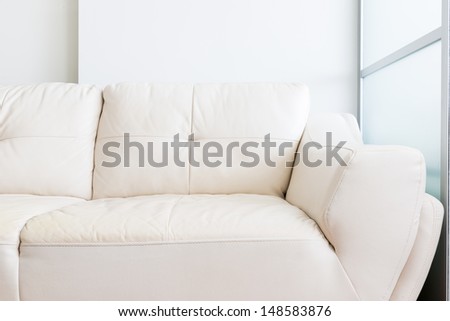white sofa near glass partition and white wall