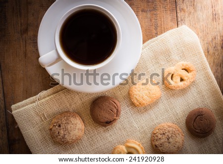 Cup of coffee and Many shapes biscuits on sackcloth and wooden table. The view from the top