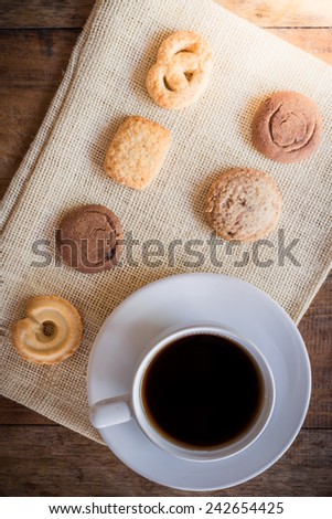 Cup of coffee and Many shapes biscuit on sackcloth and wooden table. The view from the top