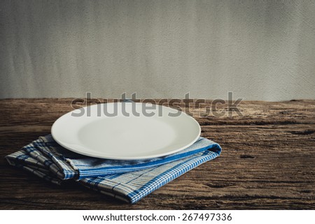 White Plate on a napkin. on wooden tabletop against grunge wall. vintage tone