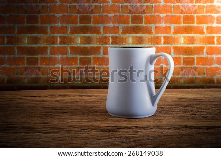 cup of coffee on wooden tabletop against grunge wall. vintage tone