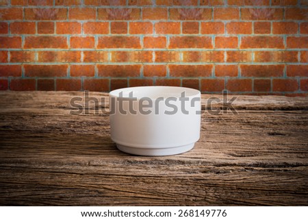 Empty little bowl on wooden tabletop against grunge wall. vintage tone