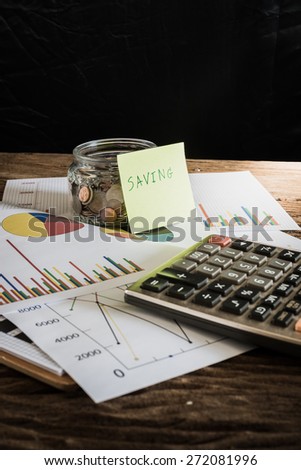 many coins in a money jar with saving label on jar, on office table. saving concept