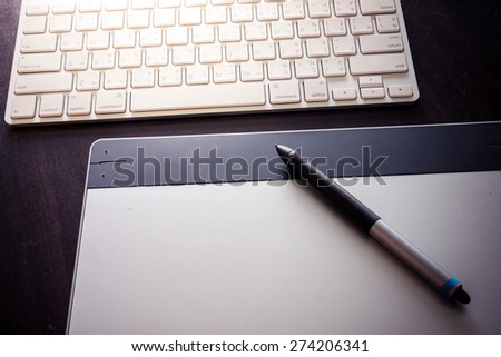 Graphic tablet with pen  and keyboard on table
