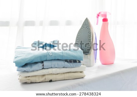 ironing, clothes, housework and objects concept, close up of iron and clothes on table at home