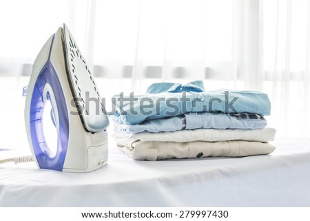 ironing, clothes, housework and objects concept, close up of iron and clothes on table at home