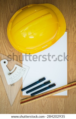 Yellow Safety Helmet Hat and clipboard and Drawing Tools on Wood background