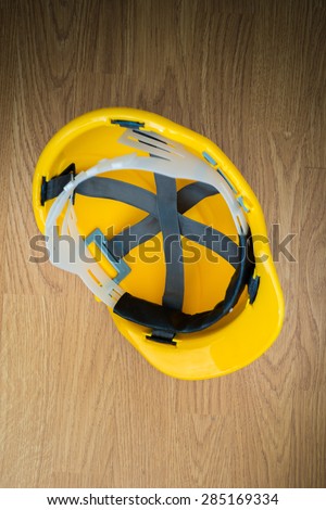 Yellow industrial protective helmet on wooden background as copy space for construction industry