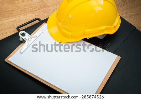 Yellow Safety Helmet Hat and clipboard and Drawing Paper Bags on Wood background
