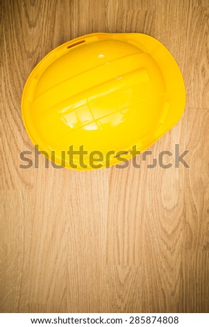 Yellow industrial protective helmet on wooden background as copy space for construction industry