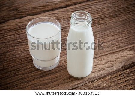 fresh milk in glass bottle and glass on wooden table