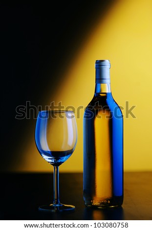 Bottle and glass of white wine on a yellow background