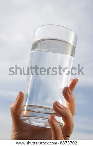 Glass of water in hand with blue sky