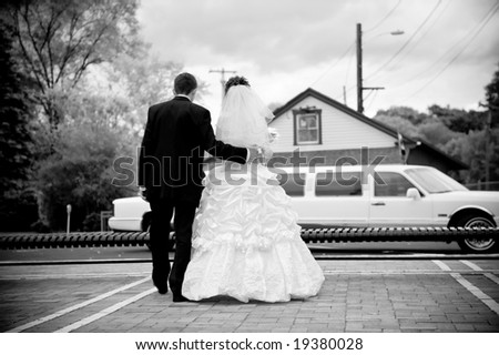 .Wedding couple goes to a limousine: a view from behind