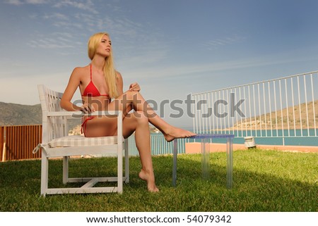 Sitting woman in a red bikini outdoors