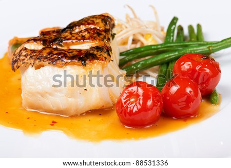 grilled fish with runner beans and cherry tomatoes on white plate
