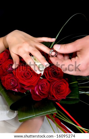 stock photo Hands over wedding bouquet with rings on black background 