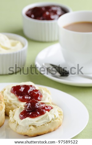 Traditional English cream tea of scones, clotted cream, strawberry jam and a cup of tea. These are served Devonshire style, with the jam on top.