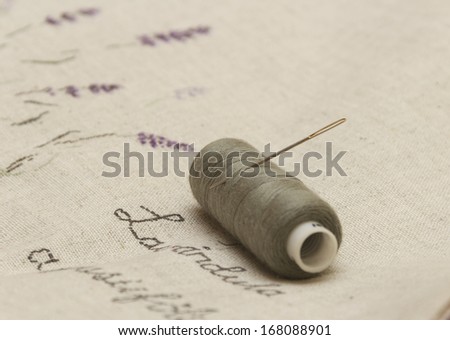 lavender flowers embroidered on linen fabric with needle and thread