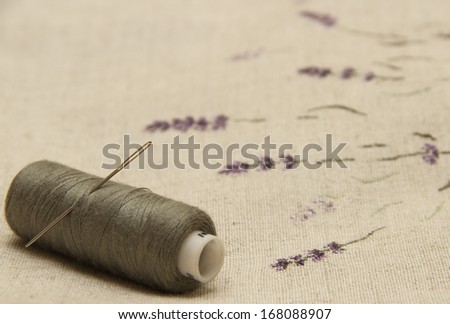 lavender flowers embroidered on linen fabric with needle and thread