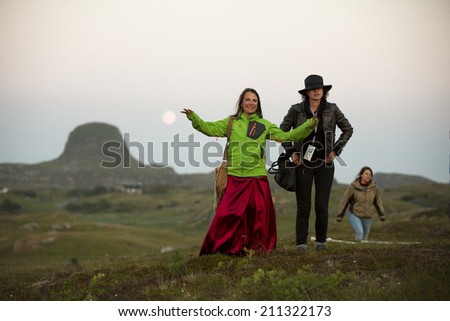 Traena, Norway - July 11 2013: at the Traenafestival, music festival taking place on the small island of Traena, woman in a red silky dress with a freind after the concert of Erlend Oye