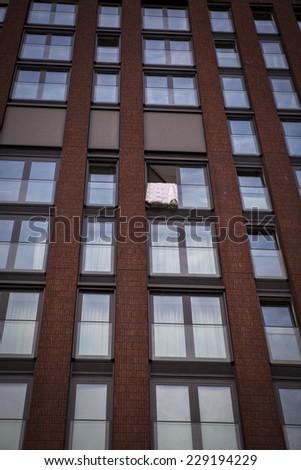 High storey building with windows and a bed cover hanging and drying