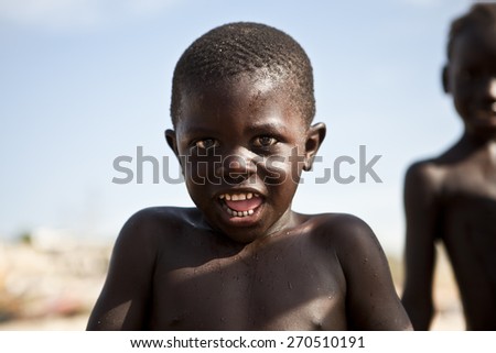 SENEGAL, Ndayane - November 9, 2013: Senegalese child on the beach of Ndayane, playing and waiting for their father to come back from fishing. Despite poverty, Senegal kids stay smiling.
